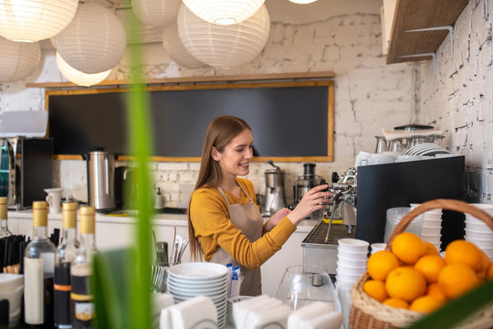 Professional barista cleaning her espresso coffee machine - Powered by Adobe