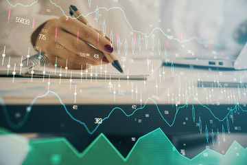 Double exposure of woman's hands making notes with forex graph hologram. Concept technical analysis.