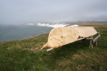 Arctic landscape with a boat on the shores of the Bering Sea. Baidara is a traditional leather boat...