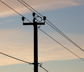 Electric pole with wires on a sunset background