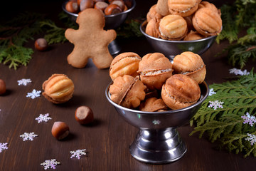 Walnut shaped shortbread cookies with cream filling in a metal cup against the dark background