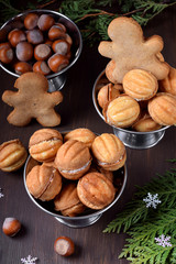 Walnut shaped shortbread cookies with cream filling in a metal cup against the dark background