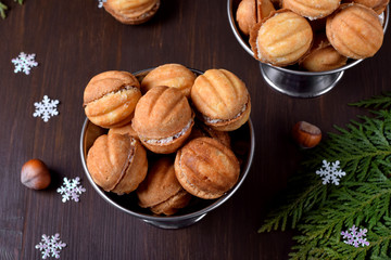 Walnut shaped shortbread cookies with cream filling in a metal cup against the dark background