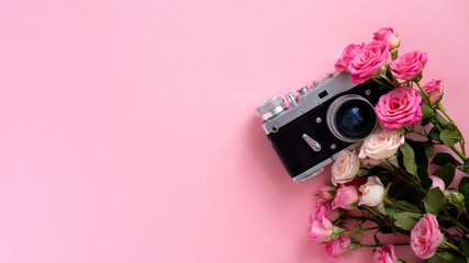 Floral composition with a wreath of pink roses and retro camera on pink background. Valentine's Day background. Flat lay, top view.