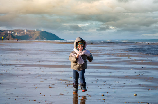 pretty little girl playing on the beach in winter