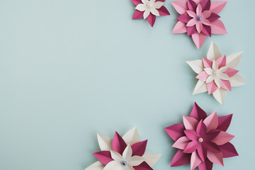 Colorful paper flowers on light background. Minimal composition in pastel colors. Spring or summer background. Top view, flat lay, copy space