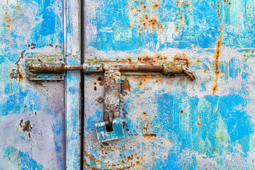 Blue padlock on a rusty metallic blue door