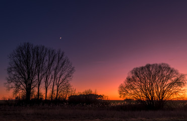 Fototapeta na wymiar An orange sunset while the moon is already waiting