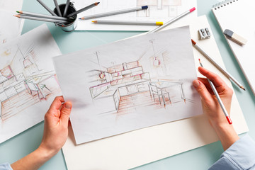 Interior designer holding  pencil sketch of a kitchen in a process of drawing.
