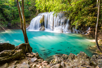 Waterfall and blue emerald water color in Erawan national park with sun light and light ray sunflare, Beautiful nature rock waterfall steps in tropical rainforest at Kanchanaburi province, Thailand