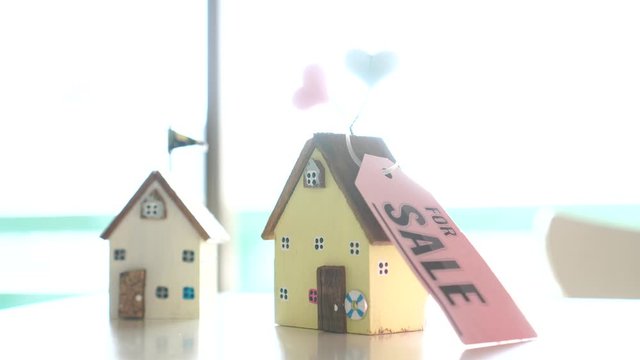 Home for sale and real estate mortgage concept: DIY little house model with tag paper "For SALE" on blur background, indicate for needs of residential for living homeowner, equity finance housing loan