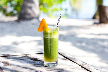Green summer drink cocktail with mango on beach