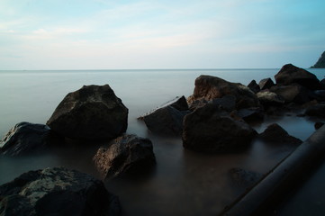 The atmosphere of the beach before the afternoon with calm waves and sunny weather against the background of the ocean and mountains