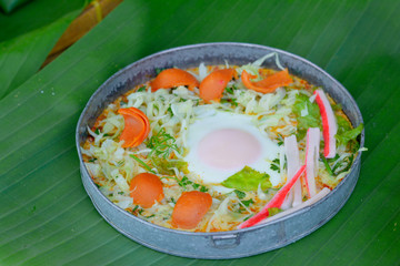Delicious egg pan with sausage ,crab stick, cabbage and lettuce in small metal pan on green banana leave. Healthy breakfast in morning.