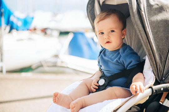 Outdoor portrait of adorable baby boy sitting in a stroller