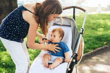 Young mother putting baby in a buggy