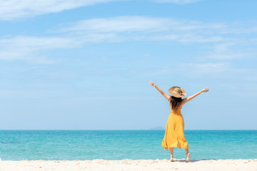 Summer Holiday. Lifestyle woman chill holding big white hat and wearing yellow dress fashion summer trips standing chill on the sandy ocean beach. Happy people enjoy and relax vacation.   copy space