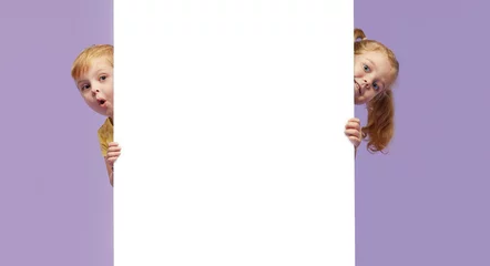 Two little children holding a white banner on purple background. Funny Faces © oes