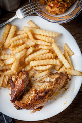 Roasted chicken with french fries on a plate.