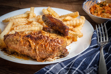 Roasted chicken with french fries on a plate.
