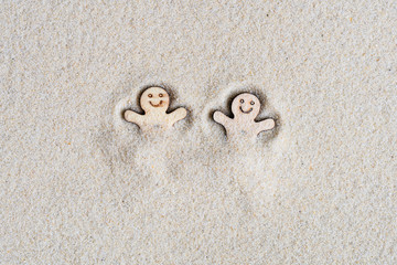 Fototapeta na wymiar Two funny happy wooden men lie on the sand at the beach. Concept. Flat lay. Aerial view