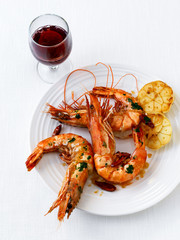 Large shrimps and prawns with fried garlic and red wine on a plate