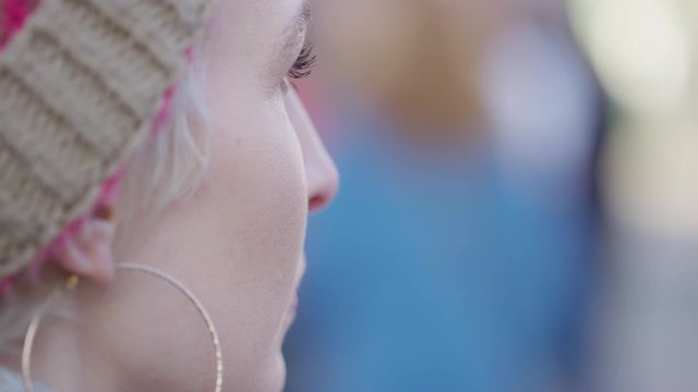 Profile shot of young woman turning around to smile and looking past camera, in slow motion
