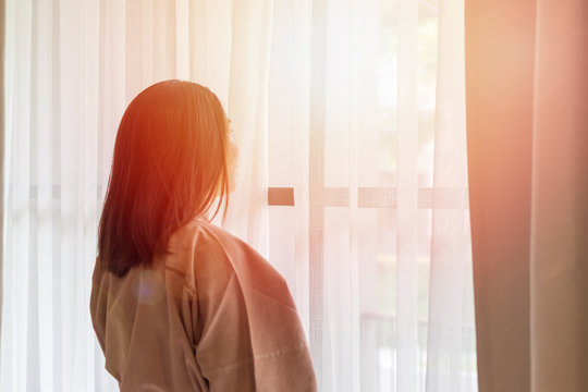 Relax Business Woman Lifestyle At Home Sitting On Modern Chair In Living Room Looking Out Of Window Toward Beautiful Cityscape Downtown Urban Landscape City Life. Happy Easy People Concept