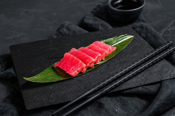 Fresh raw sashimi tuna on a stone Board. Black background. Top view - obrazy, fototapety, plakaty