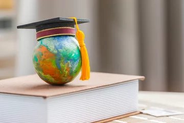 Foto op Aluminium Education to learn study in world. Graduated student studying abroad international idea. Master degree hat on top globe book. Concept of graduate educational for long distane learning anywhere anytime © smolaw11