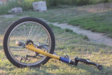 The front wheel of a bmx bicycle lying on the ground on dry grass near the trail