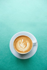 Close up of a cup of fresh cappuccino coffee on a mint background in minimal style.