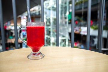 A glass full of blueberry juice placed on a wooden surface.