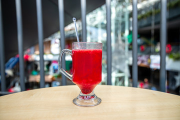 A glass full of blueberry juice placed on a wooden surface.
