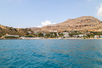 View from a boat on the water at Stegna beach with the mediterranean sea in the foreground and mountain range in the background