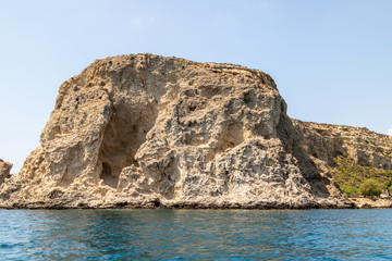 Naklejka premium View from a motor boat on the mediterranean sea at the rocky coastline near Stegna on the eastside of Greek island Rhodes