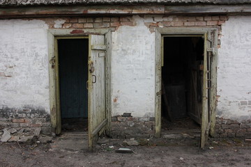  Two old open shabby doors in a white brick farmhouse. Open barn door.  Two entrances to the old pantry