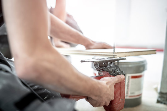 Handwerker sägt ein Stück von einer Eichendiele mit der Stichsäge von unten ab