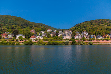 Fototapeta na wymiar Lovely panoramic landscape view of the Heidelberg residential area with its beautiful mansions across the Neckar river on a nice summer day with a blue sky.