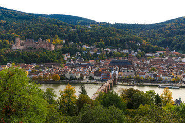 Fototapeta na wymiar Nice panorama of Heidelberg's old town with the castle on Königstuhl hill, the Church of the Holy Spirit and the Karl Theodor Bridge on the Neckar river viewed from the Philosopher’s Path in autumn. 