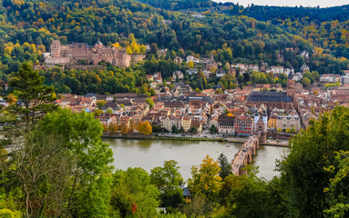 Fototapeta na wymiar Close aerial panorama of Heidelberg's old town, the castle ruin on Königstuhl hill, the church Heiliggeistkirche and the Karl Theodor Bridge on Neckar river seen from the Philosopher’s Path in autumn.