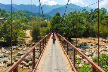 Fototapeta premium A Hmong girl walking on a bridge across stream in Sapa, Vietnam 