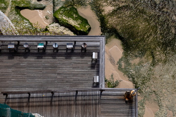 Aerial view of a decked seating area on a beach with a the sea coming in