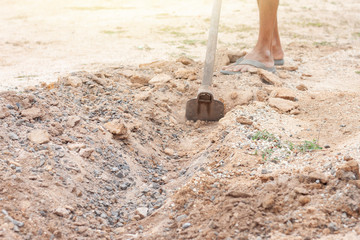 Fototapeta premium Digging the soil for making a small channel by a hoe.