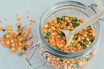 Close up glass jar with pea groats and wooden spoon. Zero waste kitchen.