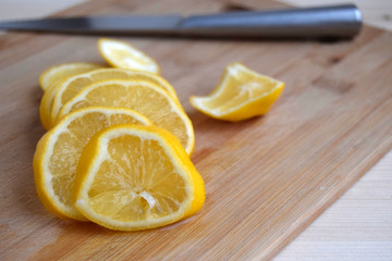 The lemon is cut. The lemon pieces are on a wooden kitchen board