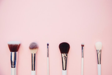 Set makeup brushes on pink color background. Top view point, flat lay