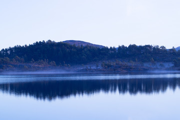 Obraz na płótnie Canvas Still lake with fog, trees and sky