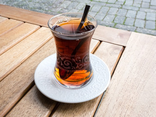 Hot Turkish tea in traditional glass with spoon on the wooden table on the street. Relaxation concept