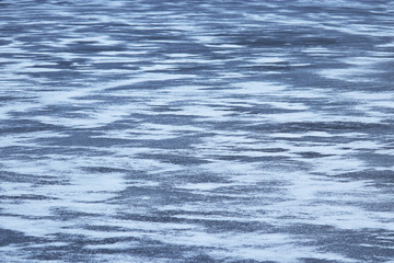 Ice covered by snow, texture of frozen winter lake. Background for cold season